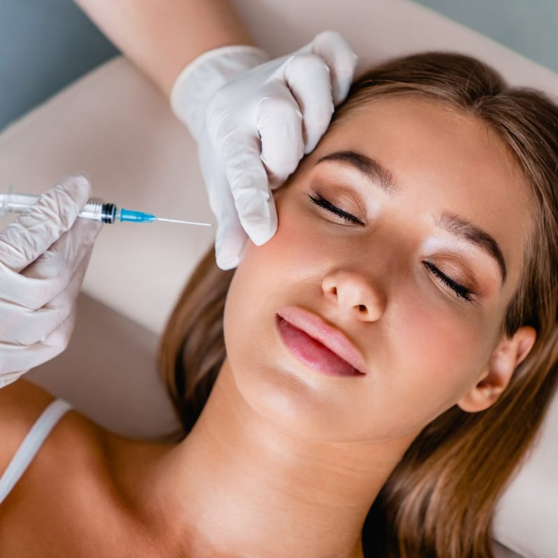 Young woman gets beauty facial injections in salon